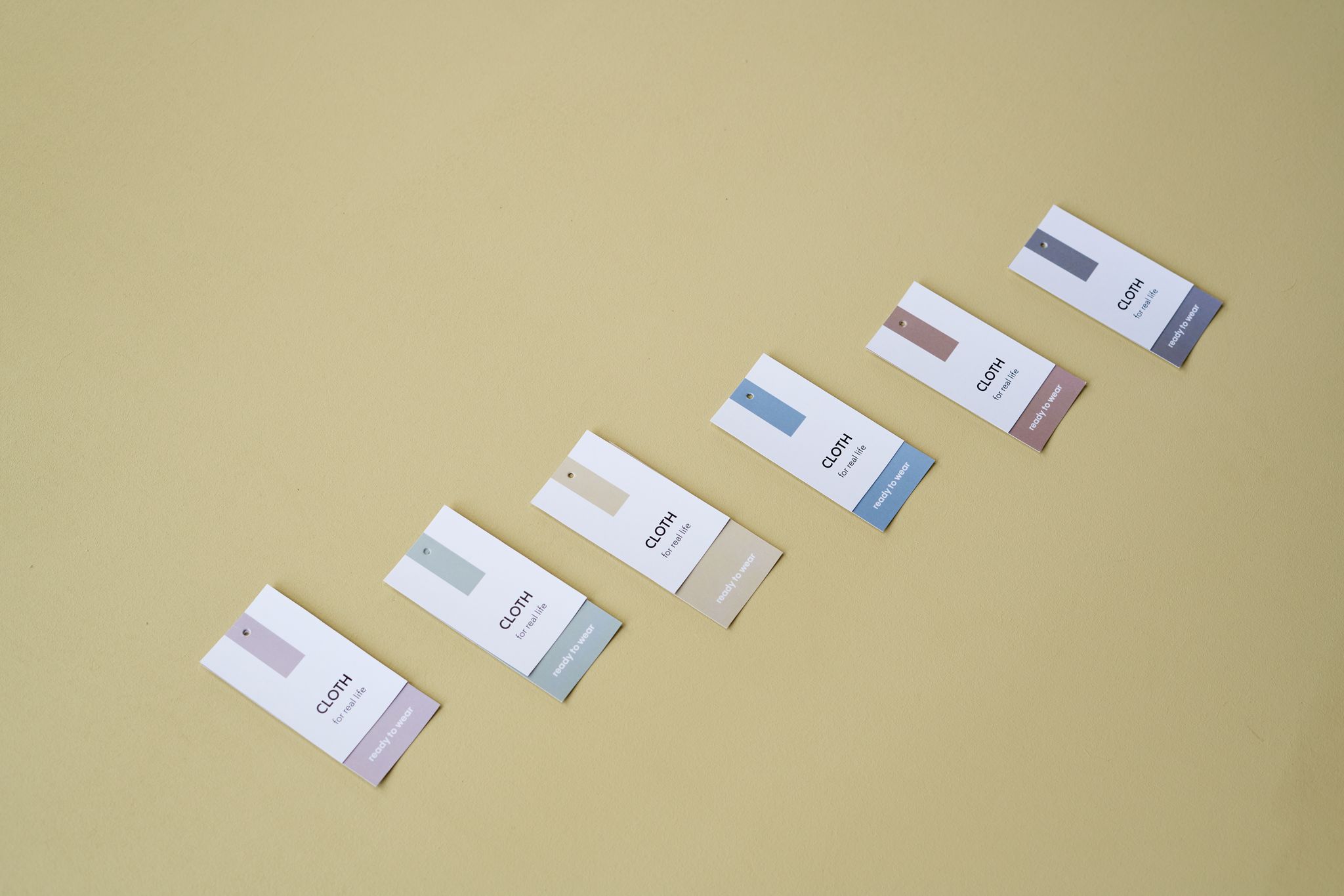 Flat lay of colorful clothing tags arranged on a yellow background.